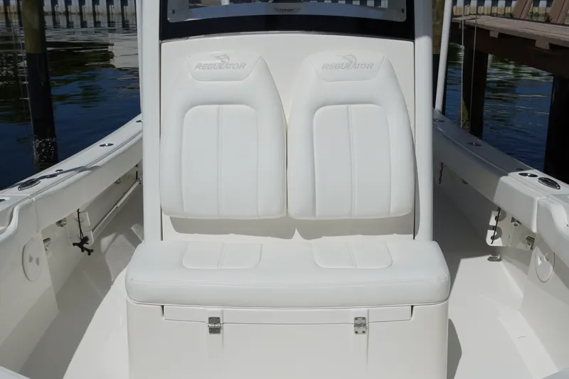 Slide: The Image of 2021 Regulator 24XO boat seating with white upholstery, docked by the water. - 25