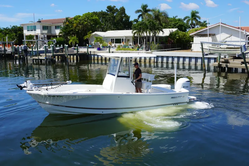 Slide: The Image of 2021 Regulator 24XO boat cruising in a scenic waterfront area with houses and docks. - 36