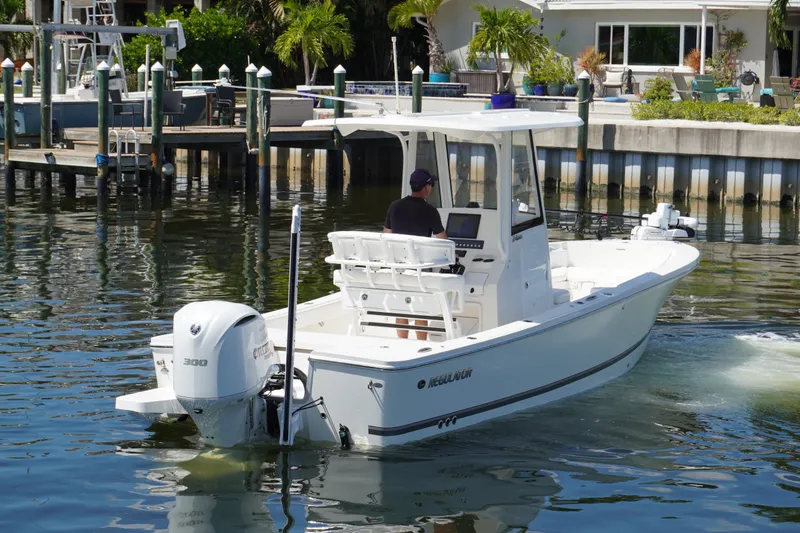 Slide: The Image of 2021 Regulator 24XO boat cruising in a marina with a Yamaha 300 engine. - 41