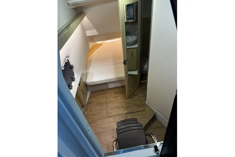 Slide: The Image of 2024 Regal 33 SAV cabin interior with bed, wooden flooring, and compact bathroom. - 7