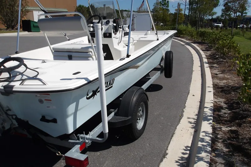 Slide: The Image of 2024 Mako Pro Skiff 17 CC boat on trailer, parked on a sunny street. - 7