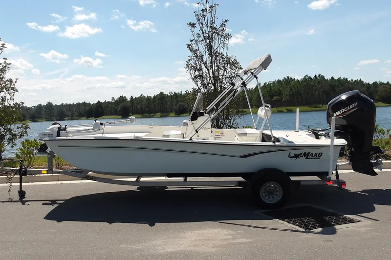 The Image of 2024 Mako Pro Skiff 17 CC boat on trailer by a scenic lake. - 1