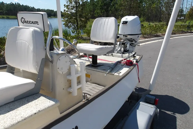 Slide: The Image of 2004 Gheenoe Classic 15 boat with white seats and outboard motor by a lake. - 6