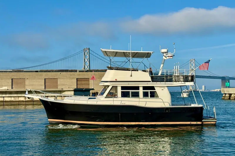 Slide: The Image of 2001 Mainship 390 Trawler cruising near a bridge on a sunny day. - 2