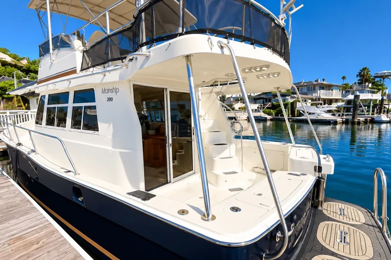 Slide: The Image of 2001 Mainship 390 Trawler docked at marina, showcasing spacious deck and elegant design. - 6