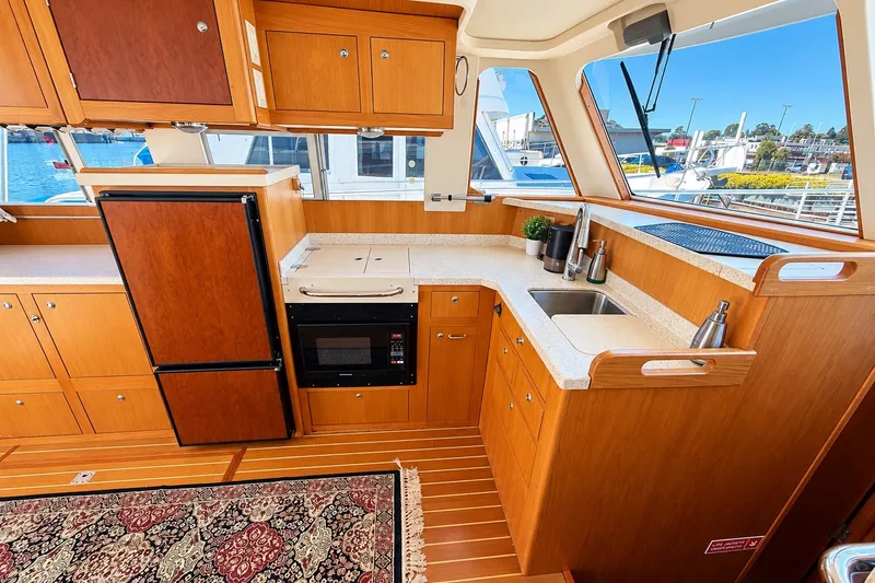 Slide: The Image of 2001 Mainship 390 Trawler kitchen with wood cabinetry, countertop, and appliances, overlooking marina. - 20