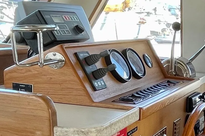 Slide: The Image of 2001 Mainship 390 Trawler helm with gauges and controls, featuring a wooden dashboard. - 9