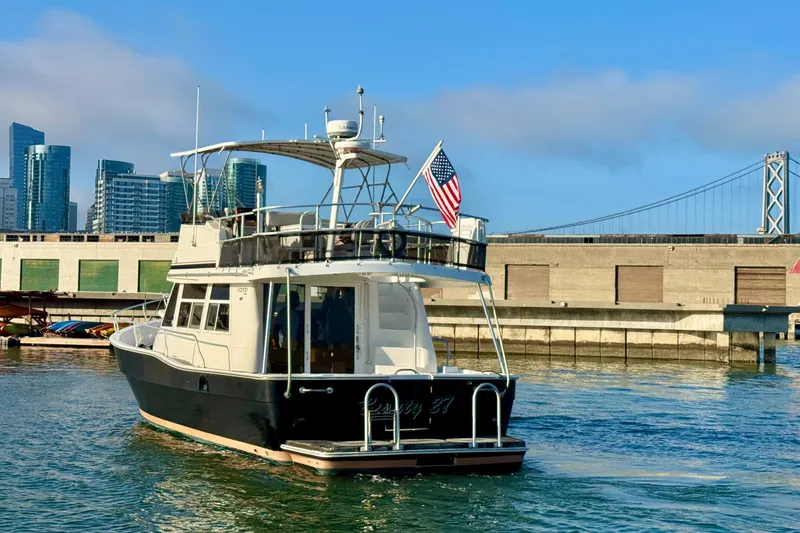 Slide: The Image of 2001 Mainship 390 Trawler cruising near urban waterfront with bridge and skyscrapers. - 4