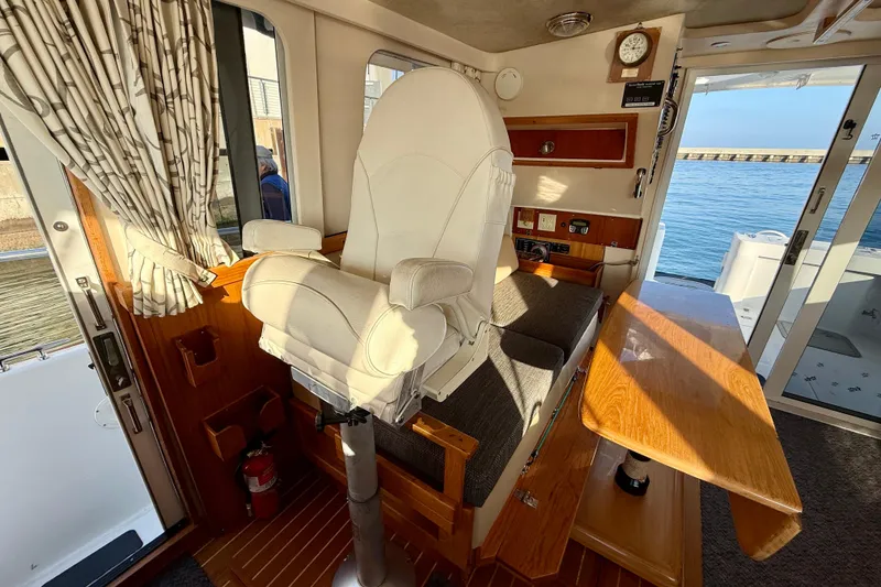 Slide: The Image of 2001 Mainship 390 Trawler interior with captain's chair, wooden table, and ocean view. - 13