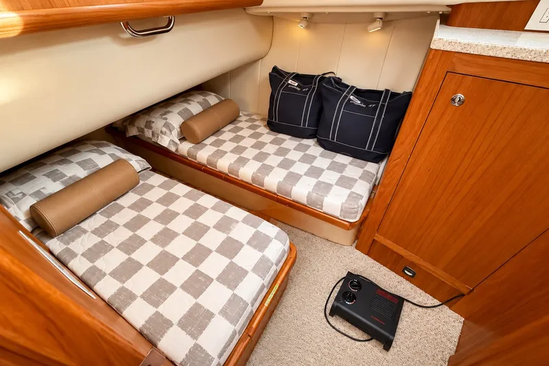 Slide: The Image of Cozy cabin with twin beds in 2001 Mainship 390 Trawler, featuring checkered bedding and wooden cabinetry. - 30