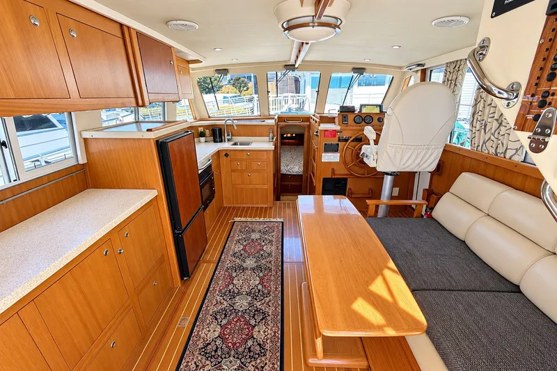 Slide: The Image of Interior of 2001 Mainship 390 Trawler with wood cabinetry, dining area, and helm station. - 17
