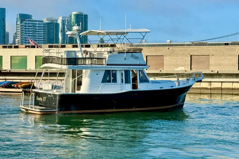 Slide: The Image of 2001 Mainship 390 Trawler docked in urban marina with cityscape background. - 5