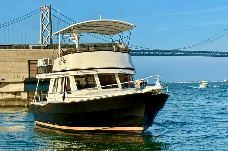 Slide: The Image of 2001 Mainship 390 Trawler cruising near a bridge on a sunny day. - 1