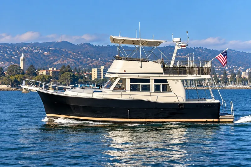 Slide: The Image of 2001 Mainship 390 Trawler cruising on water with scenic mountain backdrop. - 1