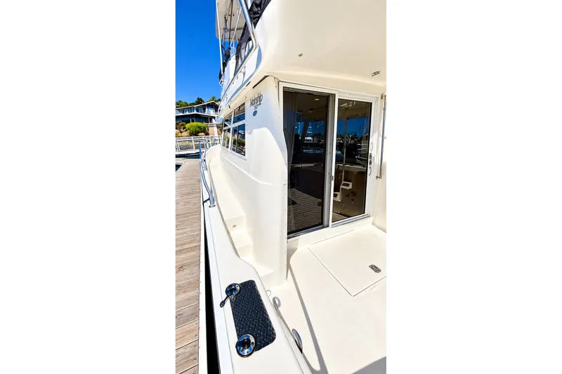 Slide: The Image of 2001 Mainship 390 Trawler docked, showcasing side deck and sliding glass door. - 9