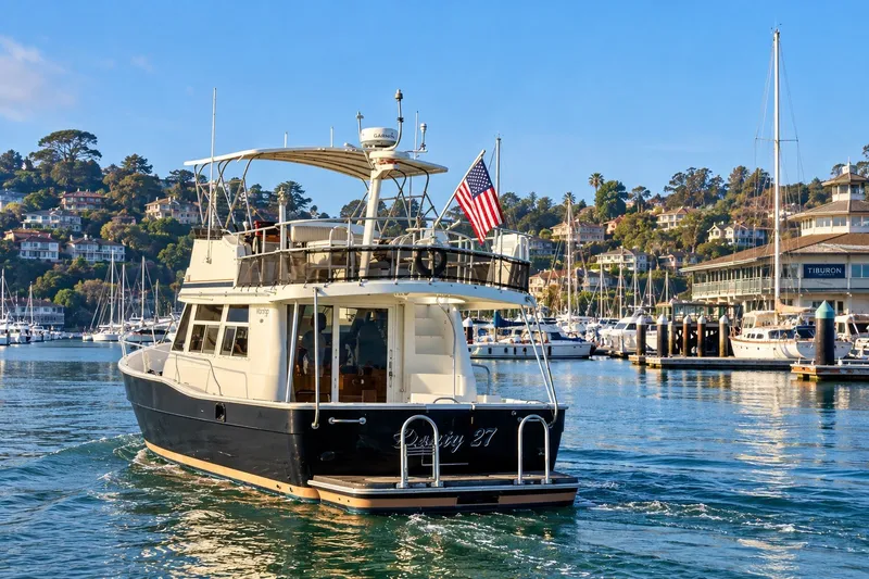 Slide: The Image of 2001 Mainship 390 Trawler cruising in a scenic marina with hillside homes. - 3