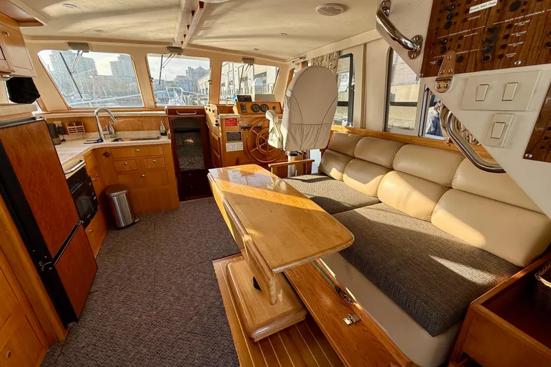 Slide: The Image of Interior of 2001 Mainship 390 Trawler with kitchen, seating, and helm in warm wood tones. - 6