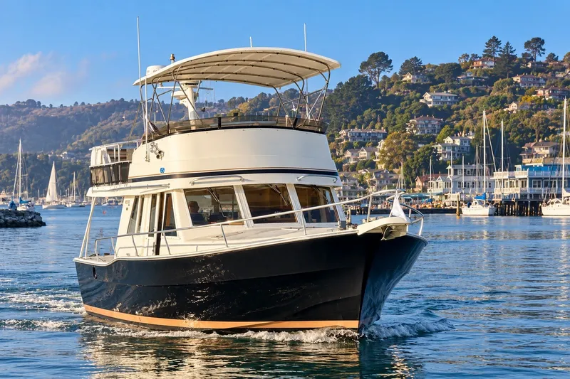 The Image of 2001 Mainship 390 Trawler cruising in scenic harbor with hillside homes in background. - 0