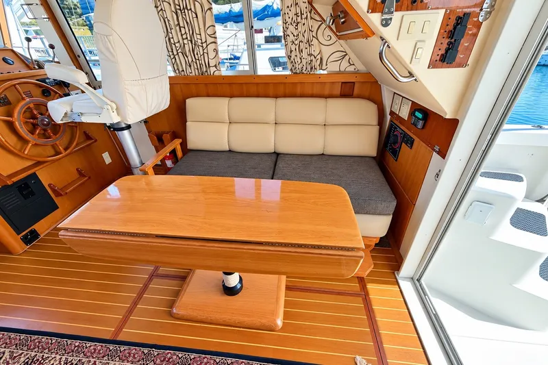 Slide: The Image of Interior of 2001 Mainship 390 Trawler with wooden table, cushioned seating, and helm station. - 19