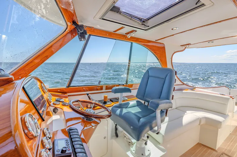 Slide: The Image of 2021 Hinckley Picnic Boat 34 MKII interior with ocean view, featuring luxurious seating and wooden helm. - 10