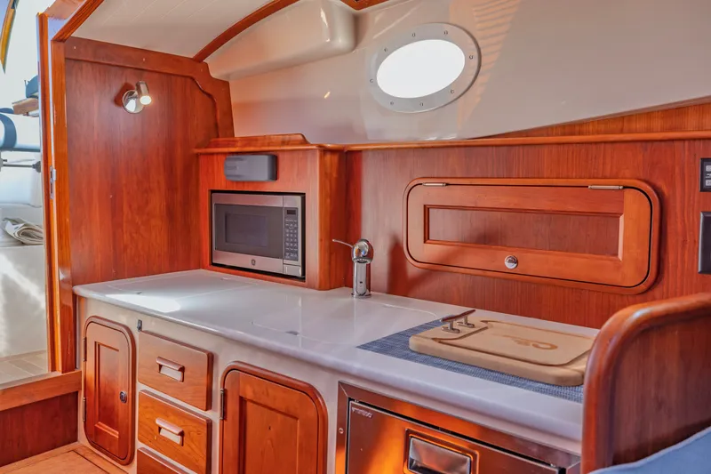 Slide: The Image of Interior of 2021 Hinckley Picnic Boat 34 MKII with wooden cabinetry and modern appliances. - 15