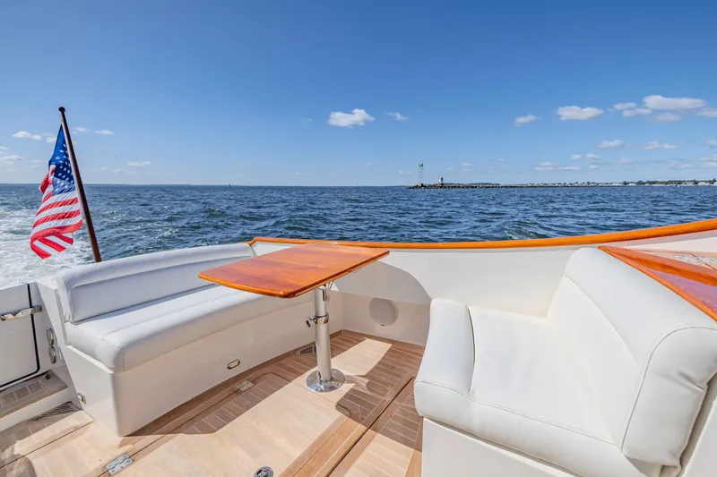 Slide: The Image of 2021 Hinckley Picnic Boat 34 MKII cruising on open water, featuring elegant seating and American flag. - 7