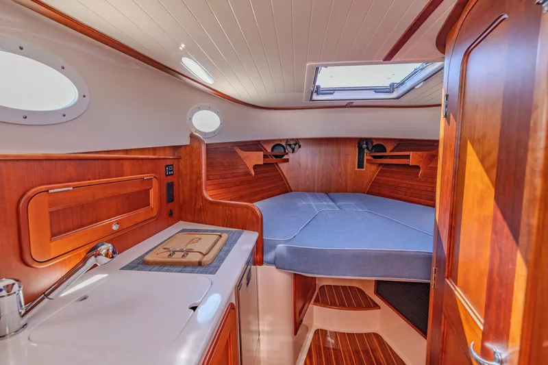 Slide: The Image of Luxurious 2021 Hinckley Picnic Boat 34 MKII cabin interior with wood finish and cozy bed. - 16