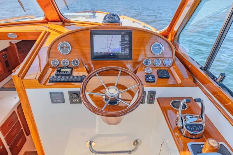 Slide: The Image of Helm of 2021 Hinckley Picnic Boat 34 MKII with wooden finish and modern navigation controls. - 12