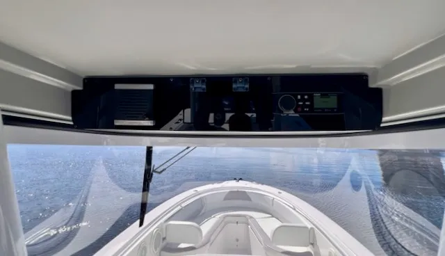 Slide: The Image of The image shows the cockpit of a 2018 Edgewater 320CC boat with a view of the water. - 30