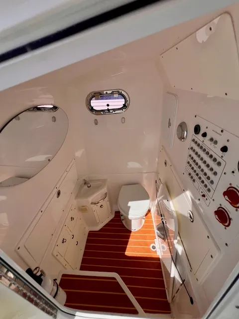 Slide: The Image of Interior view of a boat cabin with toilet, sink, and control panel. Wood flooring and porthole. - 11