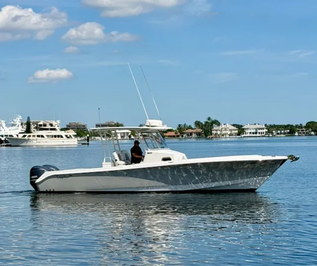 Slide: The Image of A 2018 Edgewater 320CC cruising on calm water. The sky is clear with a few clouds. - 2