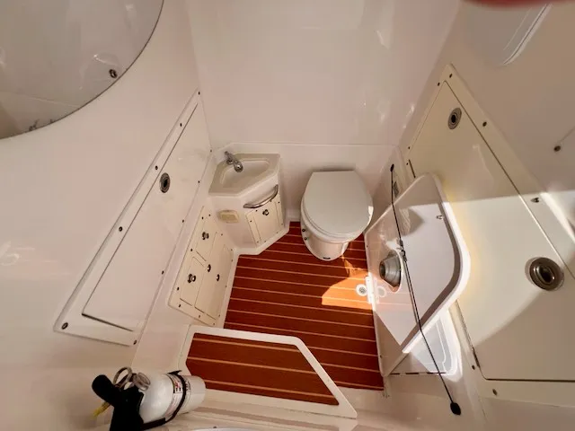 Slide: The Image of Interior of a 2018 Edgewater 320CC featuring a toilet and sink on a wooden floor. - 9