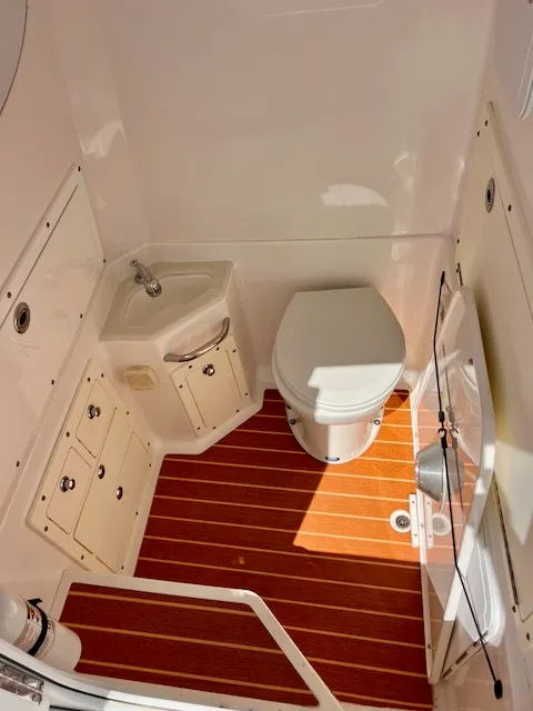 Slide: The Image of The image shows a clean, modern boat bathroom with wood flooring and white walls. - 13
