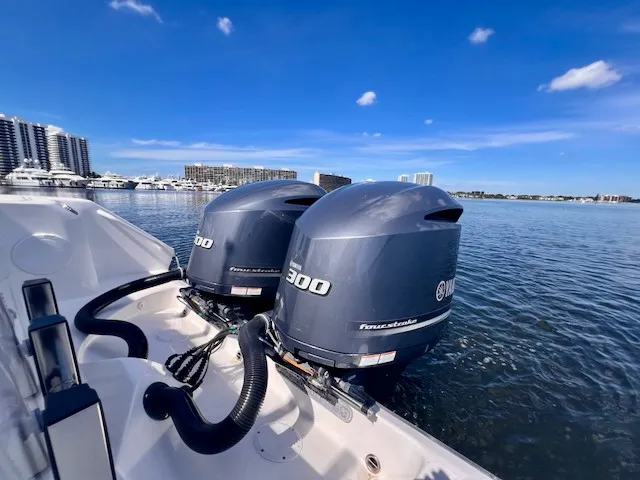Slide: The Image of Two outboard engines on an Edgewater 320CC boat on calm water with cityscape in the background. - 18