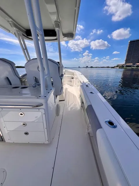 Slide: The Image of A 2018 Edgewater 320CC on calm water. It features a spacious deck and modern seating. - 14