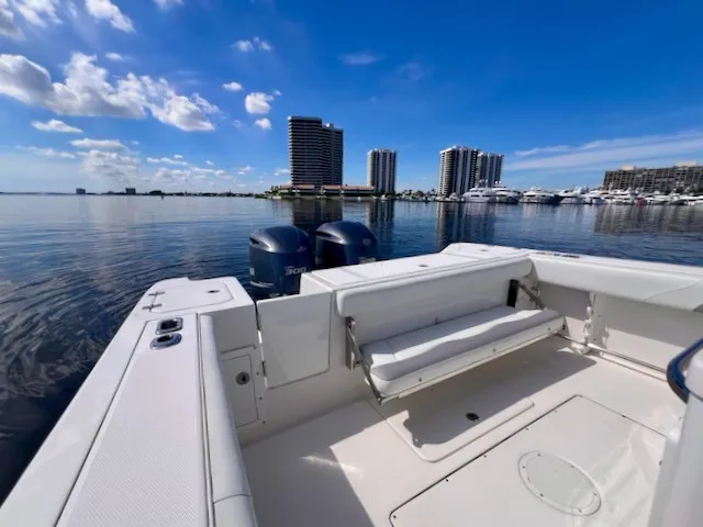 Slide: The Image of The image shows the stern of a 2018 Edgewater 320CC boat with two outboard motors. High-rise buildings and a marina are visible in the background. - 46