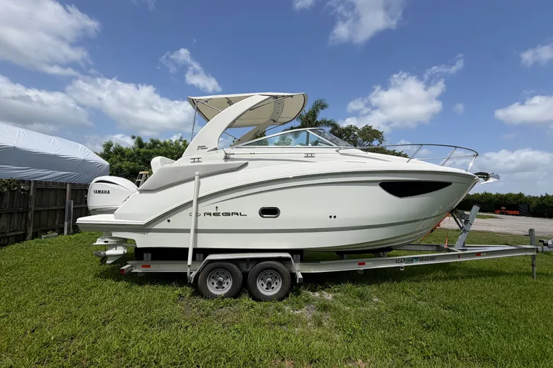 Slide: The Image of 2023 Regal 26 XO boat on trailer, side view, under clear blue sky. - 16