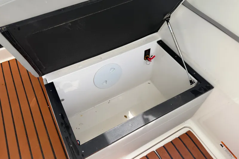 Slide: The Image of Open storage compartment on 2023 Regal 26 XO boat with teak flooring. - 7