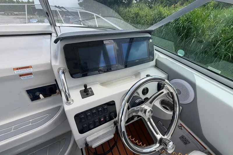 Slide: The Image of 2023 Regal 26 XO boat dashboard with steering wheel and dual display screens. - 4