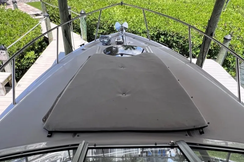 Slide: The Image of 2023 Regal 26 XO boat deck with sunpad, docked near lush greenery. - 14