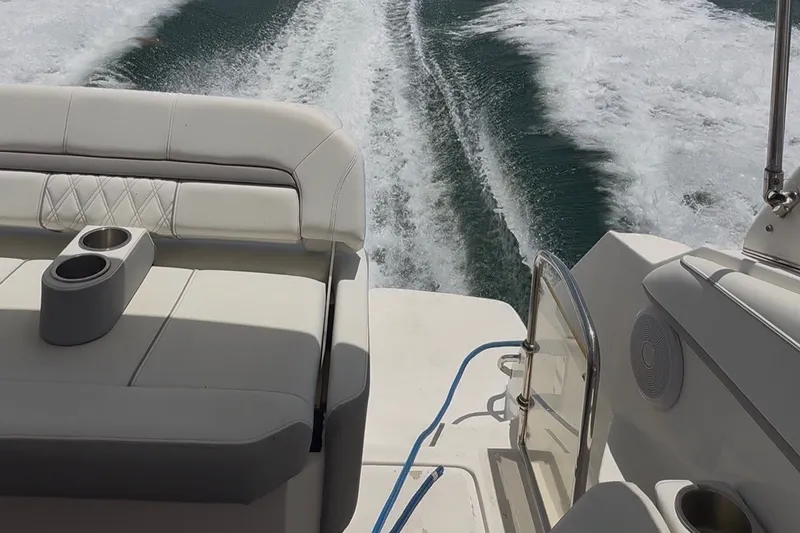 Slide: The Image of 2023 Regal 26 XO boat interior with cushioned seating and ocean wake view. - 13