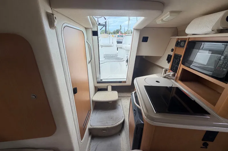 Slide: The Image of Interior of 2009 Sea Ray 240 Sundancer boat with kitchenette and seating area. - 76