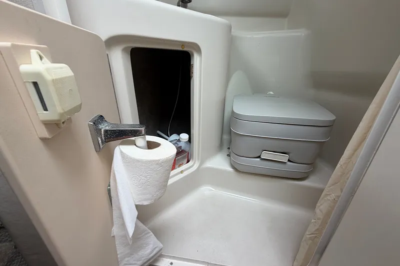 Slide: The Image of 2009 Sea Ray 240 Sundancer bathroom with portable toilet and storage compartment. - 81