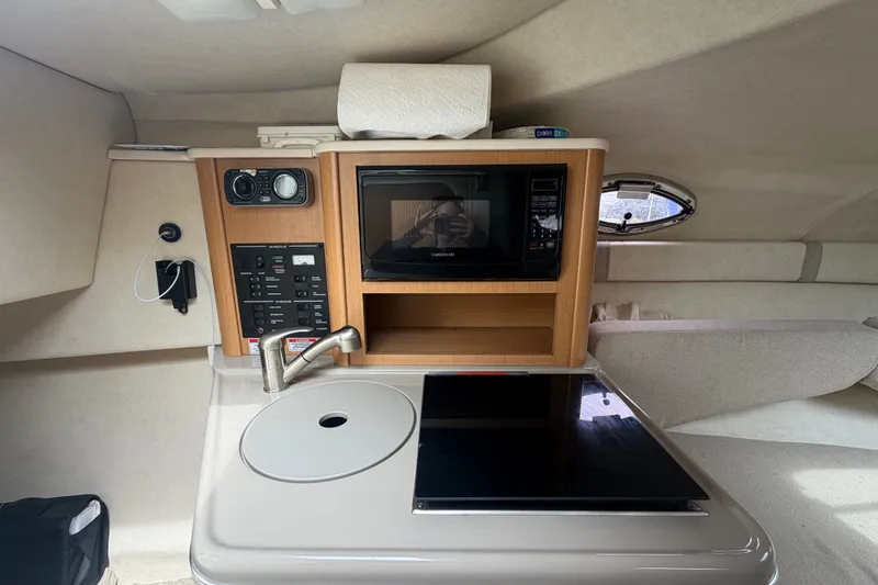 Slide: The Image of 2009 Sea Ray 240 Sundancer cabin interior with kitchenette, microwave, and control panel. - 61