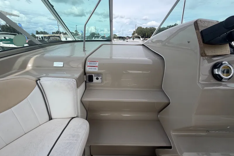 Slide: The Image of 2009 Sea Ray 240 Sundancer boat interior with beige seating and dashboard view. - 20