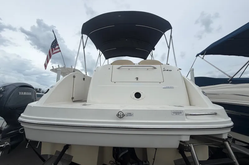 Slide: The Image of 2009 Sea Ray 240 Sundancer boat with canopy, docked alongside other vessels. - 2