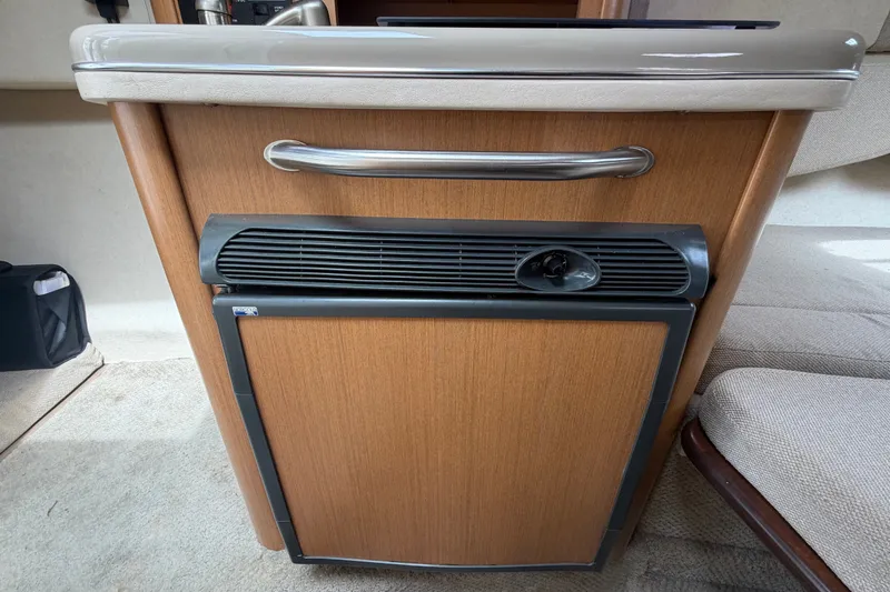 Slide: The Image of 2009 Sea Ray 240 Sundancer cabin interior with compact wooden cabinet and mini fridge. - 67