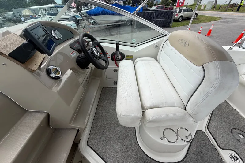 Slide: The Image of 2009 Sea Ray 240 Sundancer cockpit with steering wheel, dashboard, and white seating. - 30