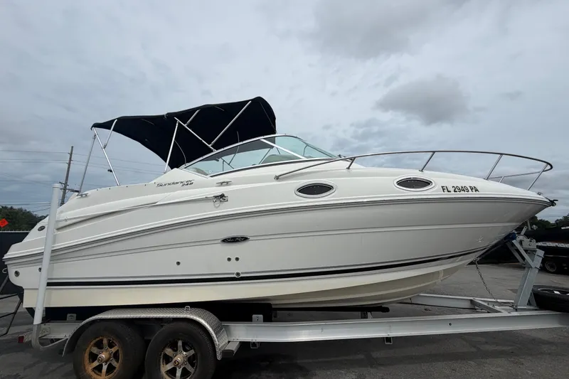 Slide: The Image of 2009 Sea Ray 240 Sundancer boat on trailer, white hull, black canopy, overcast sky. - 1
