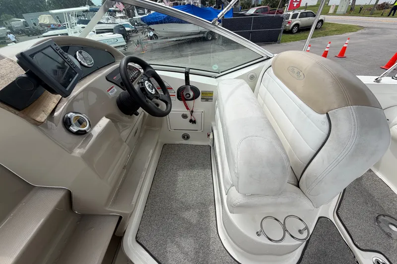Slide: The Image of 2009 Sea Ray 240 Sundancer cockpit with steering wheel, dashboard, and seating. - 31